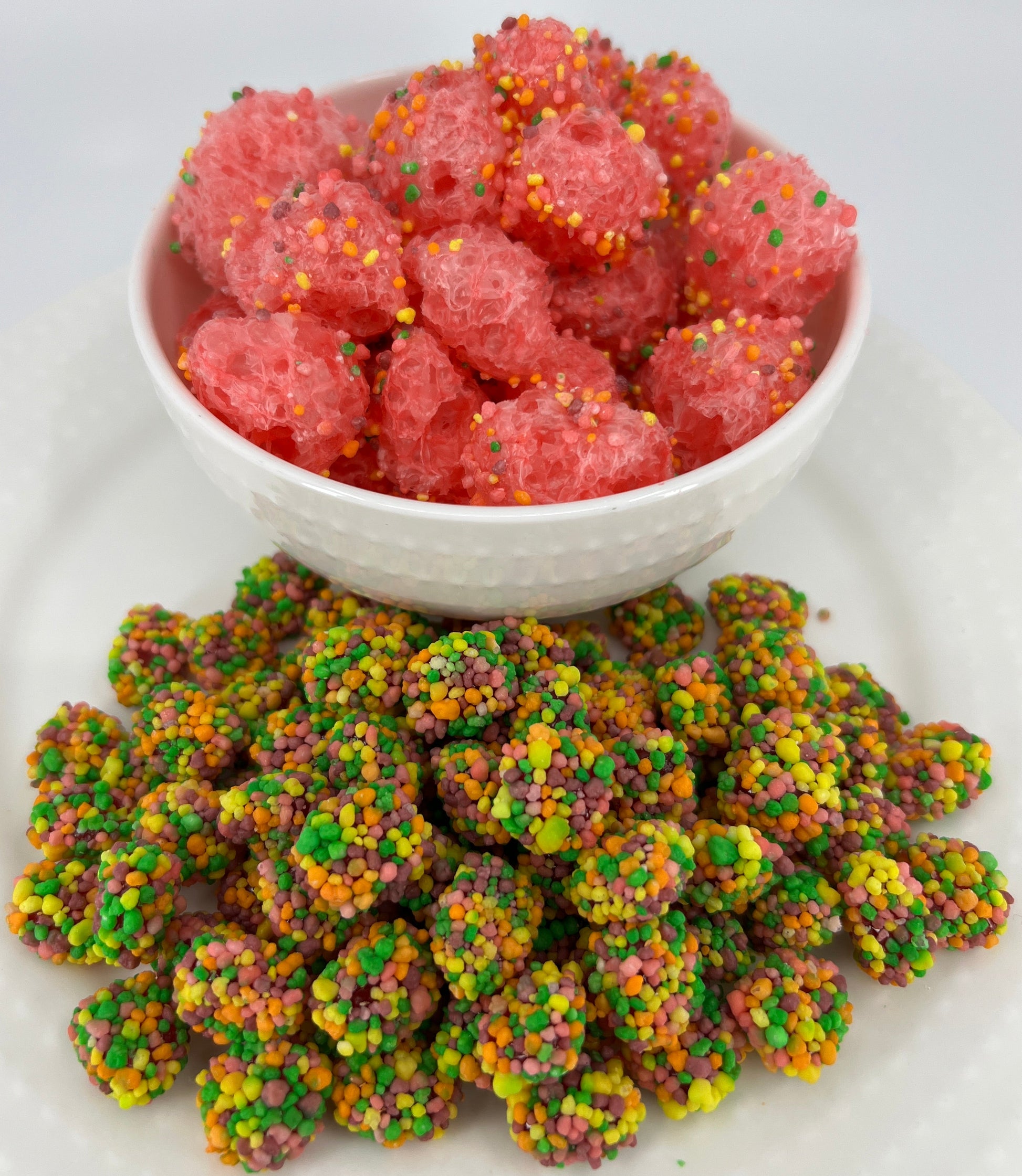 Colorful gummy candies on a white plate with a bowl