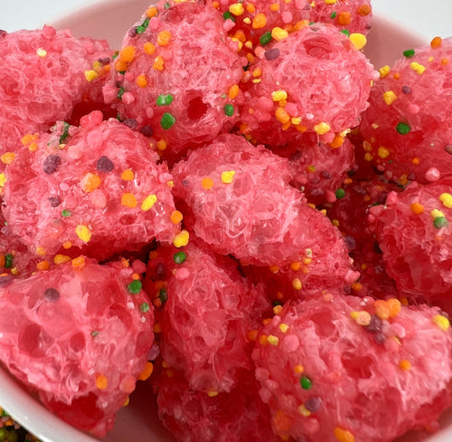 Pink dessert balls with colorful sprinkles in a white bowl
