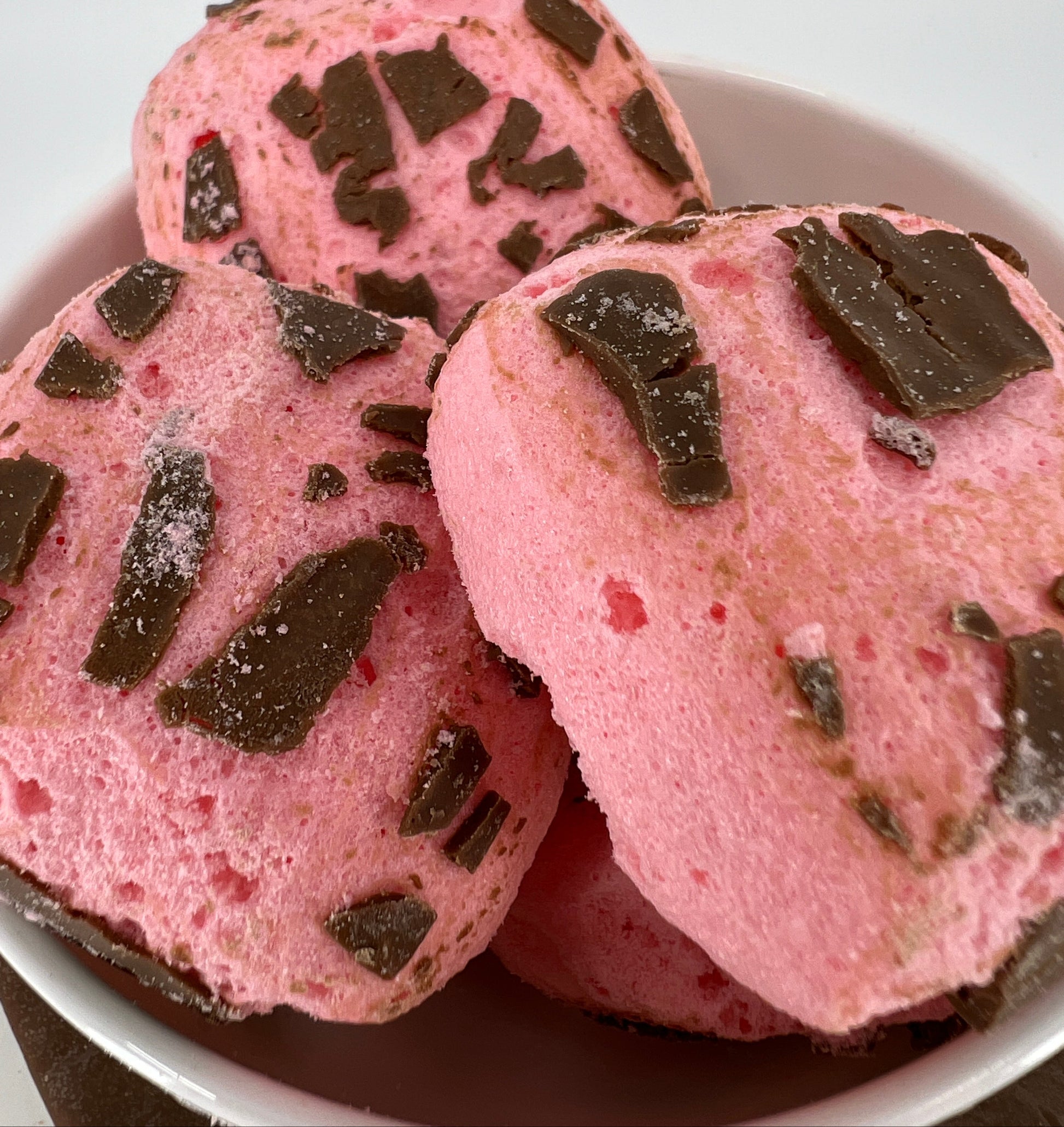 Pink cookies with chocolate chunks on a white plate