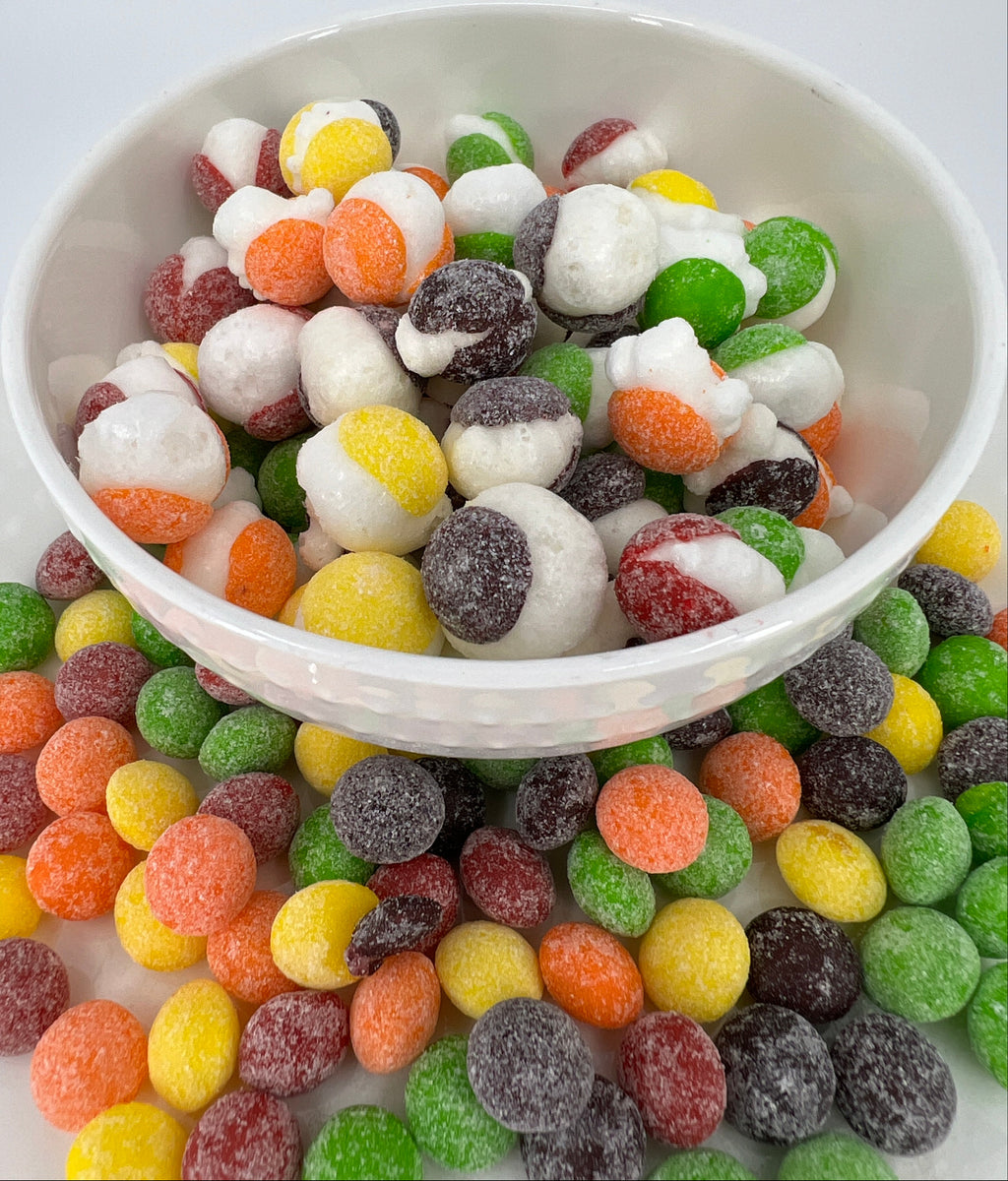 Assorted colorful gummy candies in a white bowl on a light background