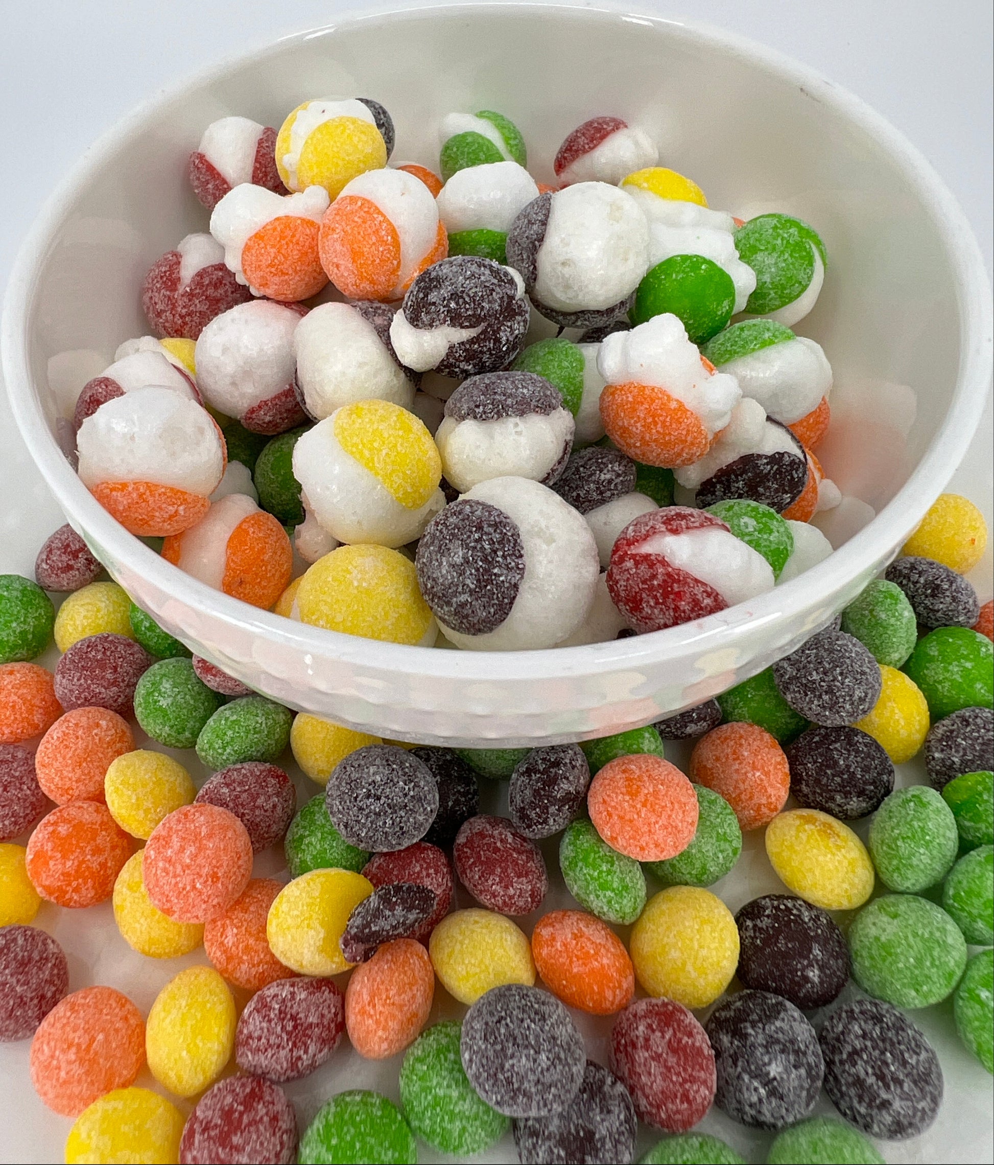 Assorted colorful gummy candies in a white bowl on a light background