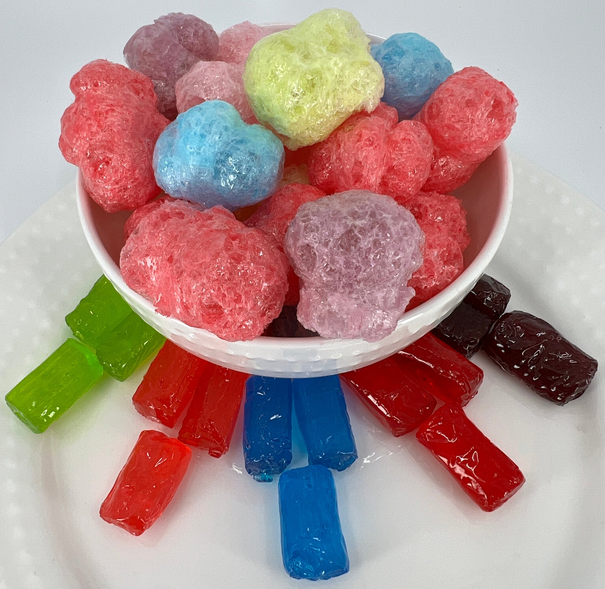 Assorted colorful gummy candies in a white bowl on a white plate