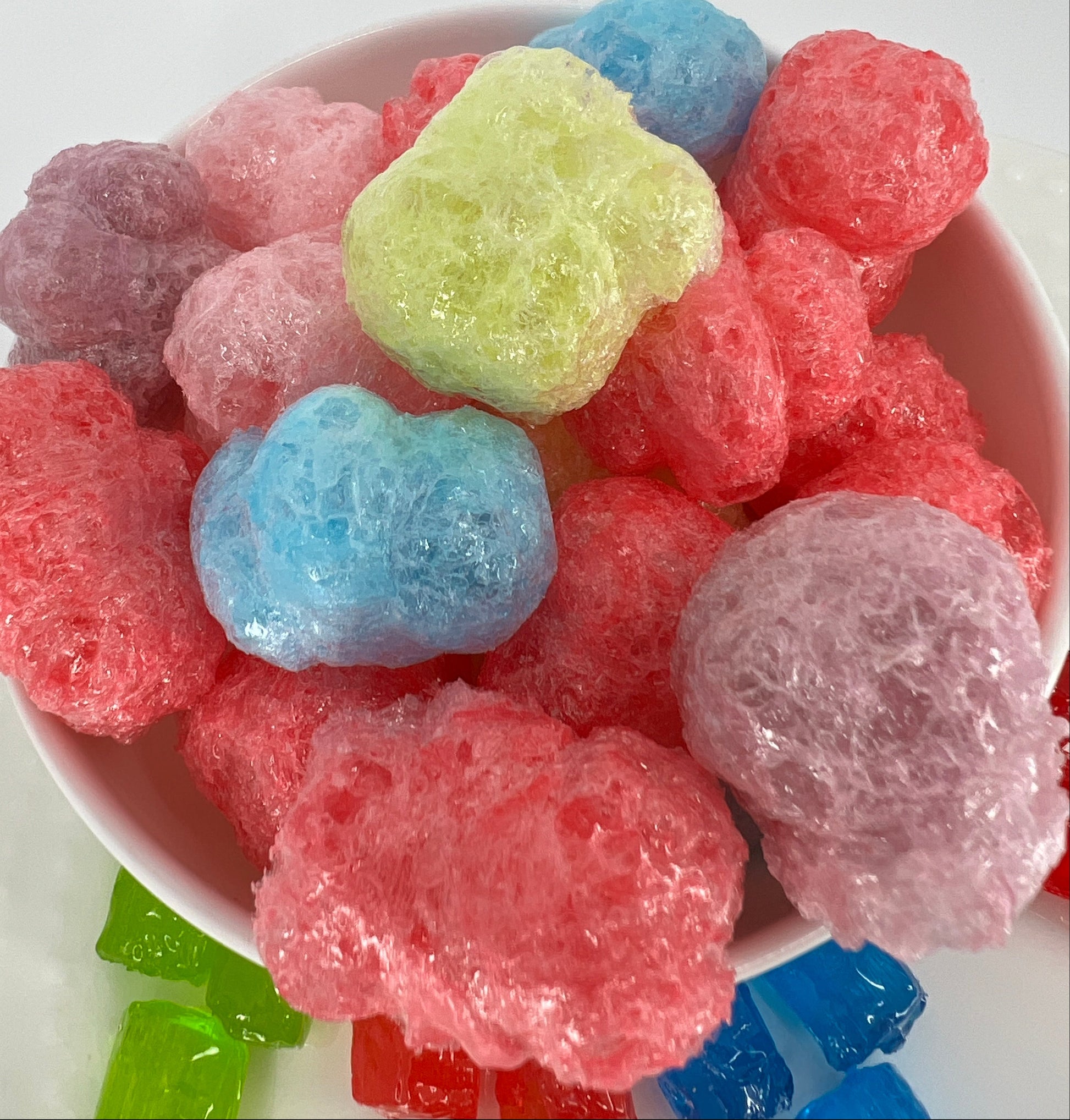 Colorful gummy candies in a white bowl on a white background