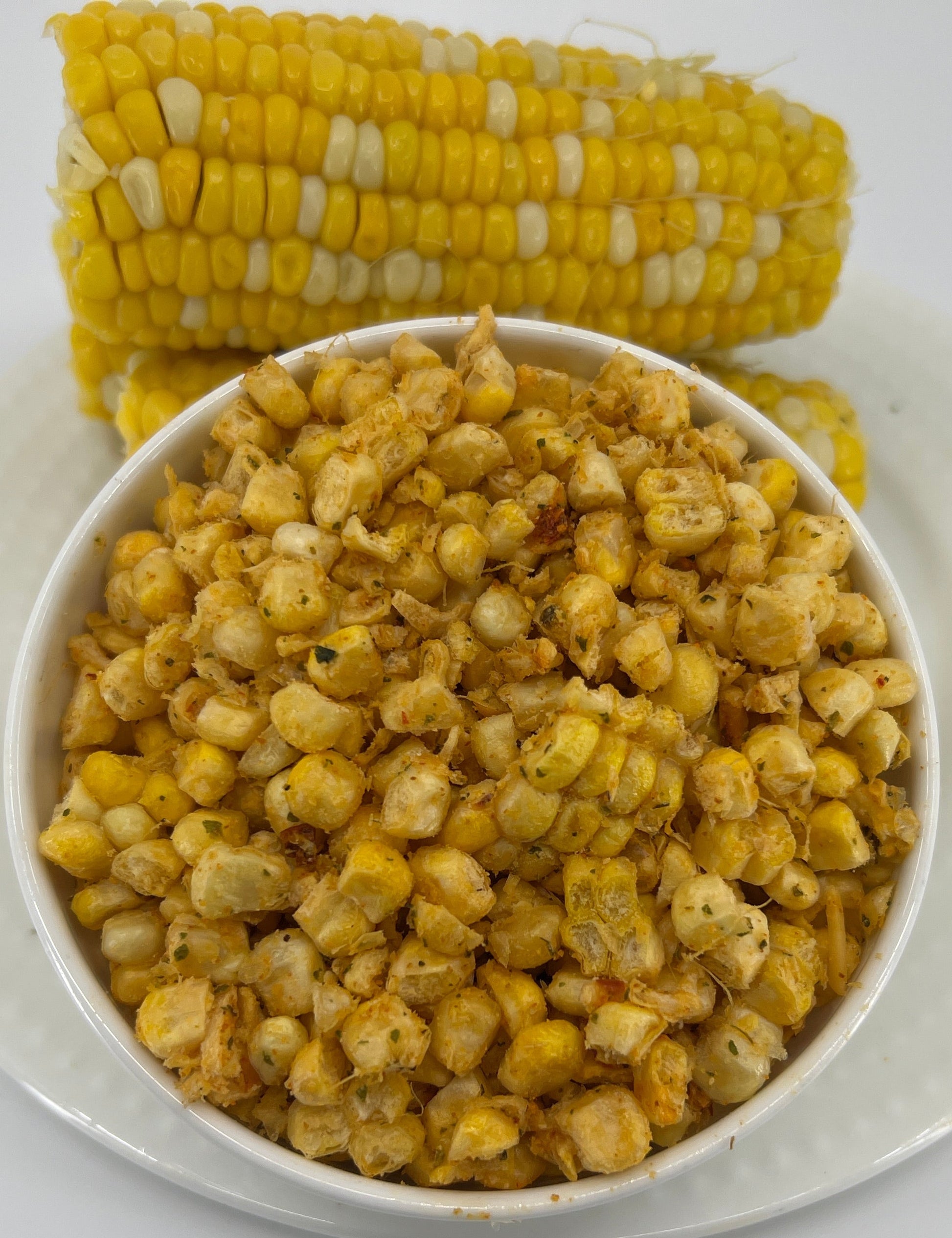 Corn kernels in a bowl with an ear of corn on a white plate